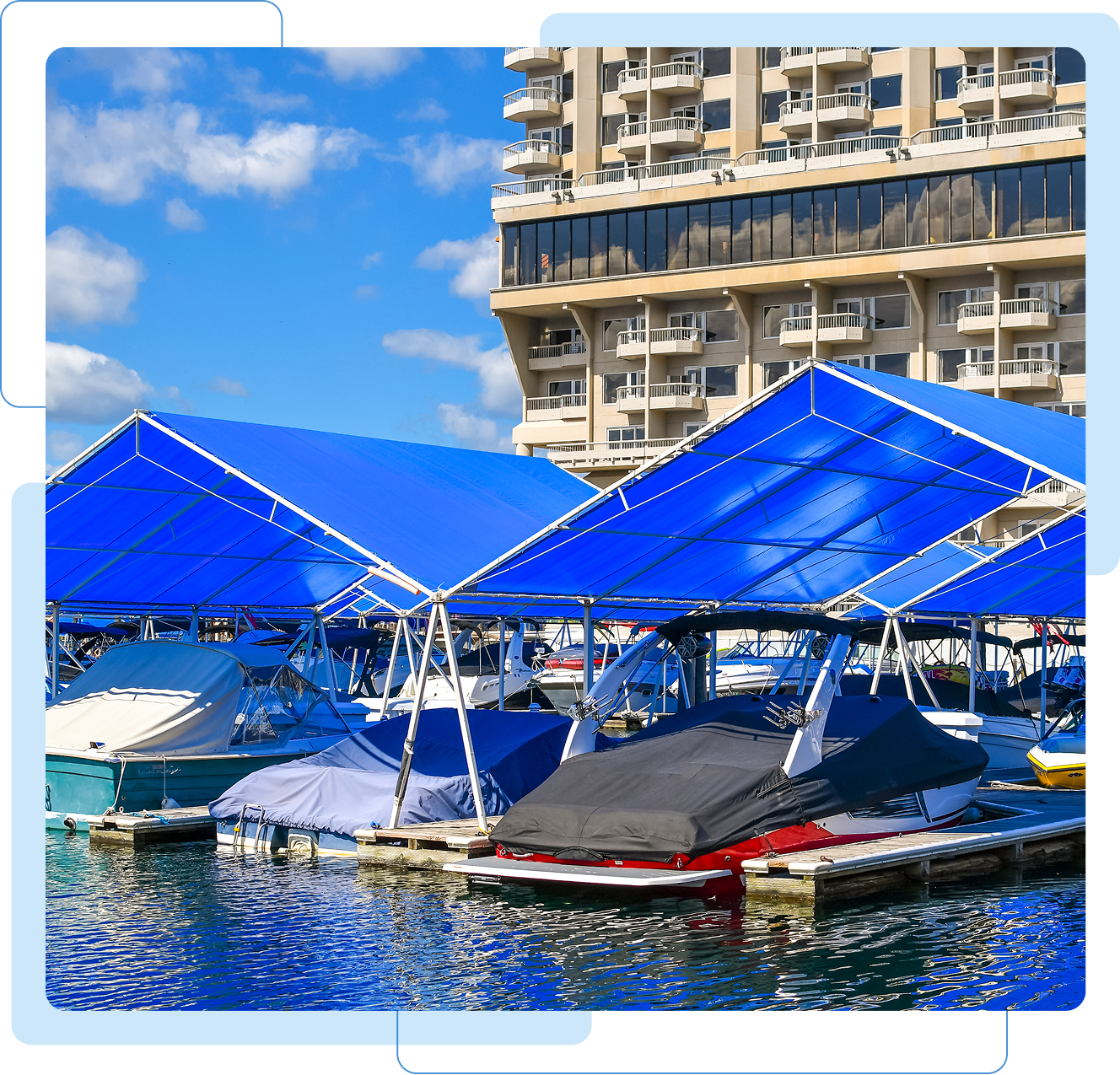 Boats docked under blue canopies near building.
